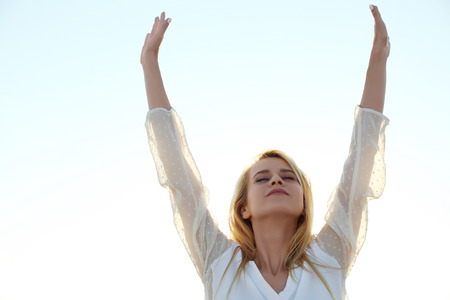 Happy young woman on sky backgroundの写真素材