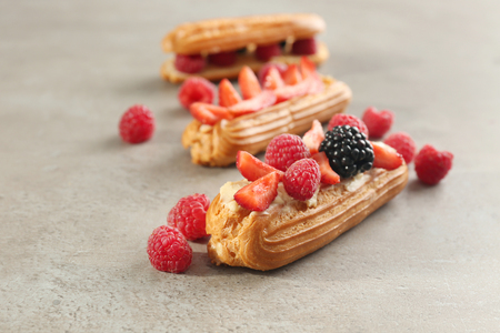 Delicious eclairs with berries on light textured backgroundの写真素材