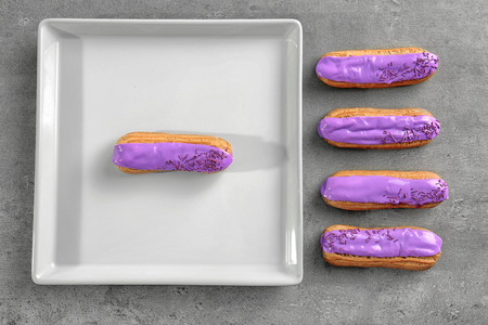 White tray and delicious glazed eclairs on light textured background