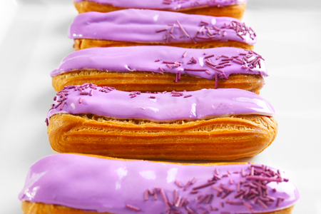 Delicious glazed eclairs on white background
