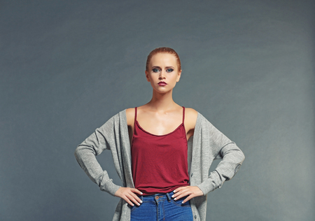 Pretty young blonde woman in casual clothes against grey backgroundの写真素材