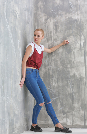 Pretty young blonde woman in casual clothes against grunge backgroundの写真素材