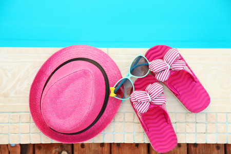 Pink hat, sunglasses and flip flops by   swimming poolの写真素材