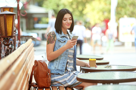 Young beautiful  girl sitting outdoors with cup of coffeeの写真素材