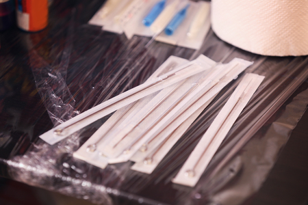 Sterile needles for tattoo machine on wooden table, close up viewの写真素材