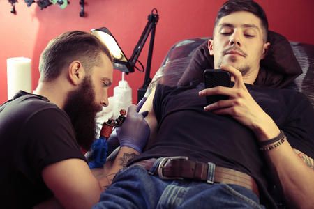 Professional artist making tattoo in salonの写真素材