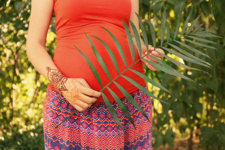Young pregnant woman with henna tattoo on hand in parkの写真素材