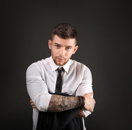 Young tattooed man posing on dark backgroundの写真素材