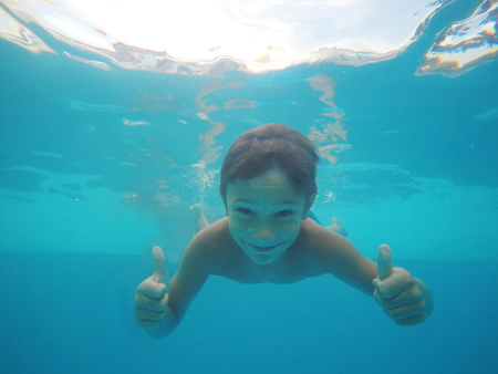 Little boy swimming underwater in poolの写真素材