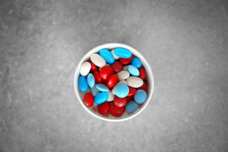 Delicious candies in paper cup on gray background