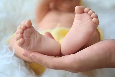 Woman hand holding bare baby feet, close up viewの写真素材