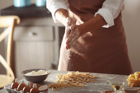 Man preparing pasta on kitchen table, close up view