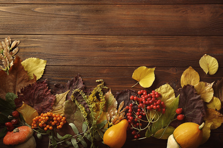Autumn composition of leaves, vegetables and berries on wooden background. Thanksgiving day conceptの写真素材