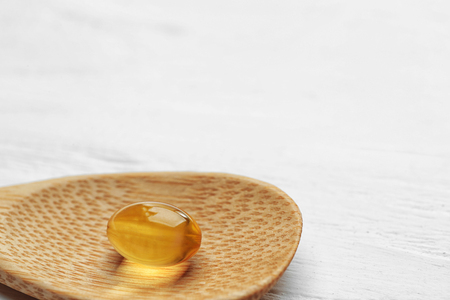 Wooden spoon with cod liver oil pill, closeupの写真素材