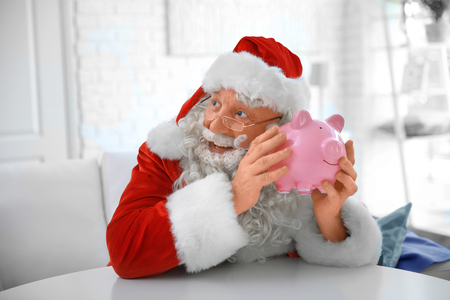 Santa Claus with piggy bank at homeの写真素材