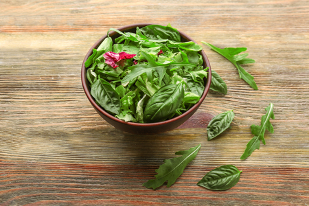 Bowl with mixed salad leaves on wooden tableの写真素材