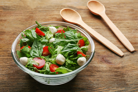 Fresh healthy salad in a glass bowl on wooden tableの写真素材