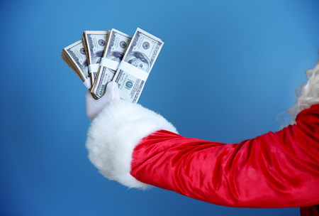 Santa Claus hand holding money on blue backgroundの写真素材