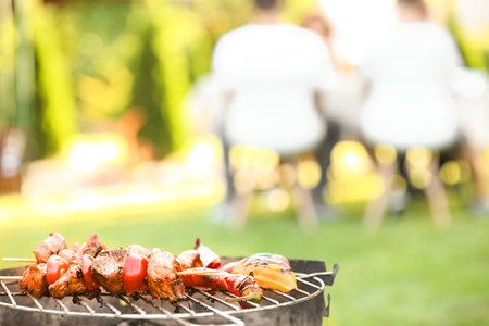 Tasty meat and vegetables on barbecue grill against blurred background, close up viewの写真素材