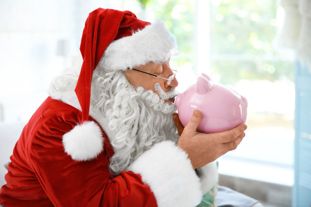 Santa Claus with piggy bank at homeの写真素材