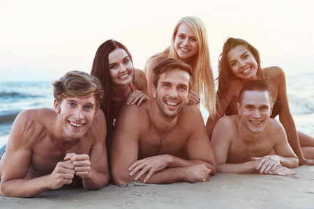 Happy friends lying on beach sandの写真素材