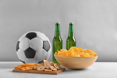 Beer with snacks and football ball on light backgroundの写真素材