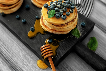 Delicious pancakes with blueberries, honey and mint on wooden cutting boardの写真素材