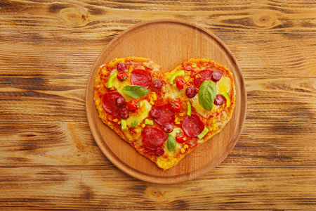 Tasty heart shaped pizza on wooden backgroundの写真素材