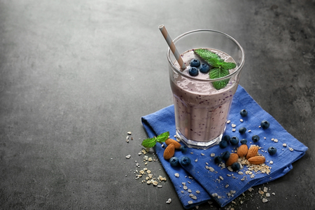 Glass of tasty smoothie and some ingredients on grey tableの写真素材