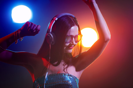 Portrait of pretty young DJ with headphones in nightclub
