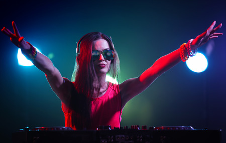 Pretty young DJ playing music in nightclubの写真素材