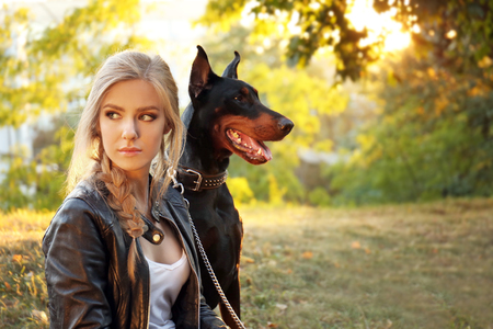 Beautiful young woman and her dog in green parkの写真素材