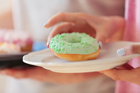 Female hand taking tasty donut from plate, close up viewの写真素材