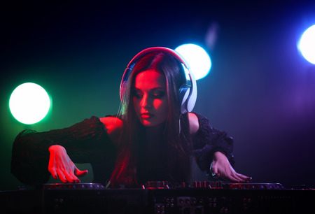 Pretty young DJ playing music in nightclub