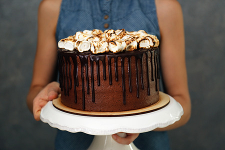 Woman holding chocolate cake with marshmallow on grey backgroundの写真素材