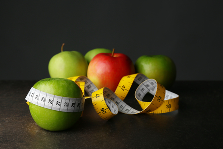 Fresh apples with measuring tape on dark tableの写真素材