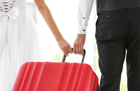 Groom and bride with big suitcase indoorsの写真素材