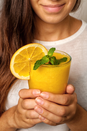 Woman holding glass of delicious orange milk shake, closeupの写真素材