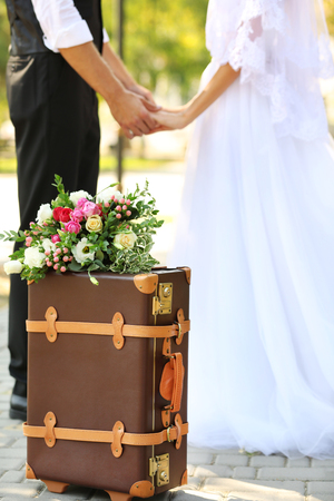 Vintage suitcase and groom with bride on backgroundの写真素材