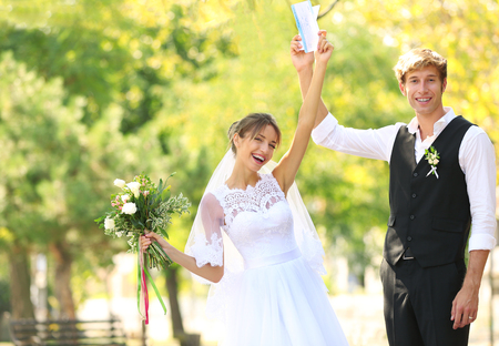 Bride and groom with tickets in parkの写真素材