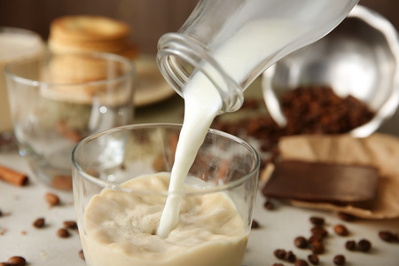 Pouring milk into a glass on table, closeupの写真素材