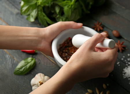 Female hands grinding spices in mortar