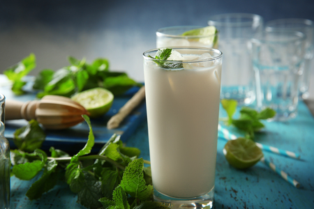 Glass of tasty milk shake with lime and mint on table, closeupの写真素材