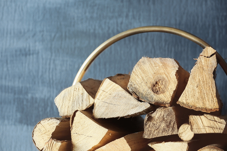 Stack of firewood against textured wall, close up view
