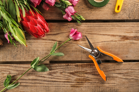 Beautiful flowers and florist equipment on wooden backgroundの写真素材