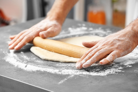 Male hands preparing dough for pizza on table closeupの写真素材