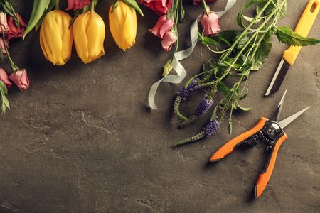 Beautiful flowers and florist equipment on dark backgroundの写真素材