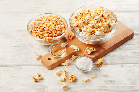 Bowls full of traditional popcorn and corn grain on wooden tableの写真素材