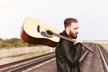Handsome man with guitar on railroad