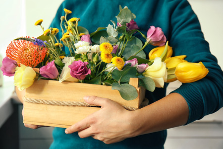 Female florist holding beautiful flower composition in box, closeupの写真素材